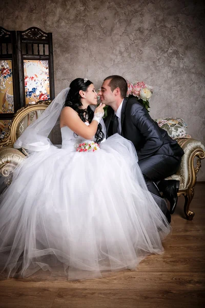 Lo sposo felice e la sposa si siedono su un divano — Foto Stock