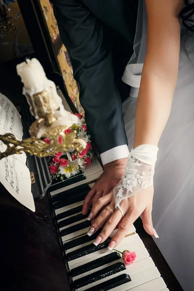 Mãos de homem casado e mulher com anéis de casamento que põem em chaves de piano com rosas bege quase — Fotografia de Stock