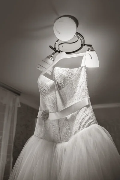 Wedding dress is hanging on the chandelier in the room — Stock fotografie