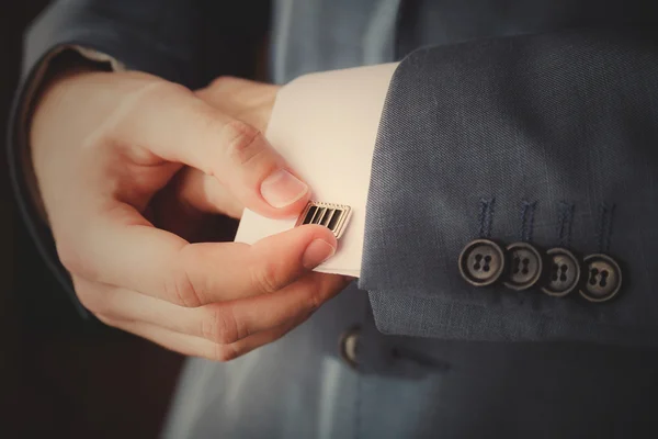 Groom putting on cuff-links as he gets dressed in formal wear close up — Stock Photo, Image