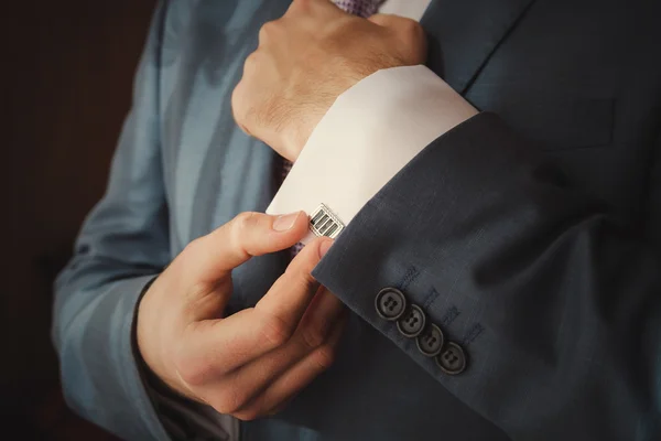 Groom putting on cuff-links as he gets dressed in formal wear close up — Stock Photo, Image