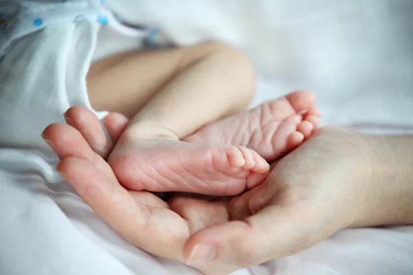 Ноги ребенка в материнской руке крупным планом — стоковое фото