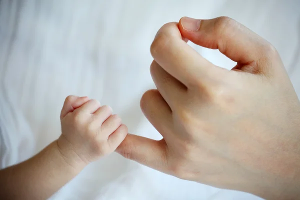 Mão do bebê recém-nascido agarrando o dedo da mãe Imagens Royalty-Free
