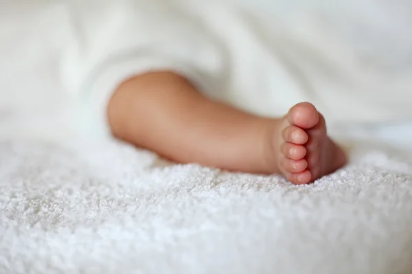 Новорожденная детская нога на белом одеяле — стоковое фото