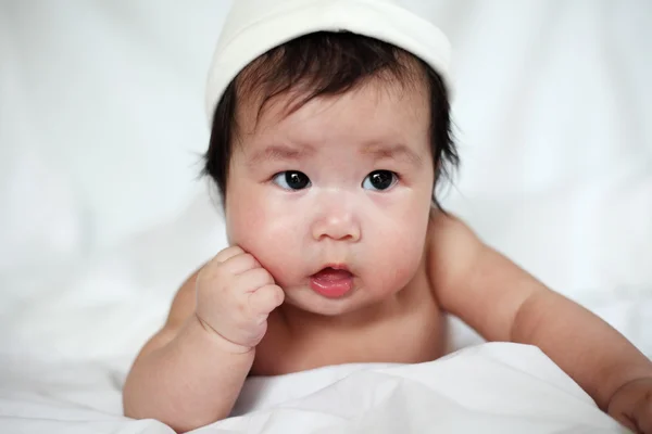 Солодкий новонароджений дитина в білому капелюсі бреше на ліжку — стокове фото