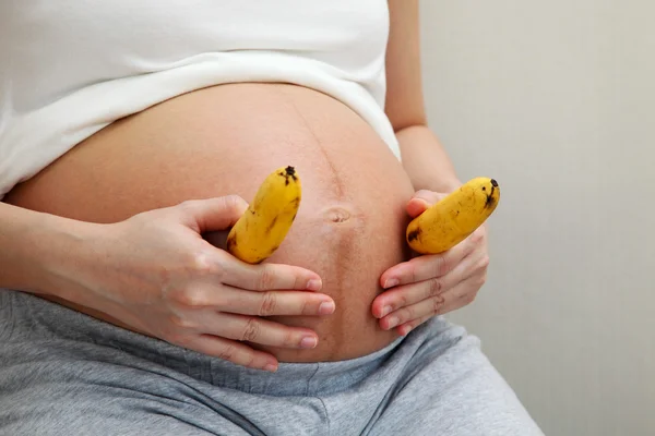 Mulher grávida segurando bananas — Fotografia de Stock