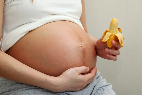 Mujer embarazada sosteniendo plátano Fotos de stock