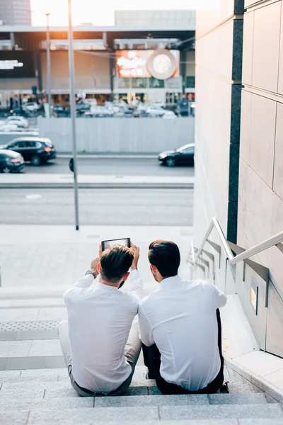 Des hommes d'affaires modernes assis sur un escalier — Photo