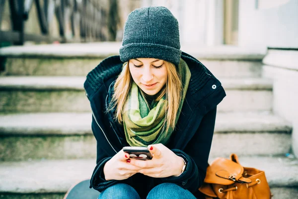 Kobieta siedzi na schody z inteligentny telefon — Zdjęcie stockowe