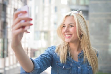 bir selfie alarak bir akıllı telefon kullanan kız