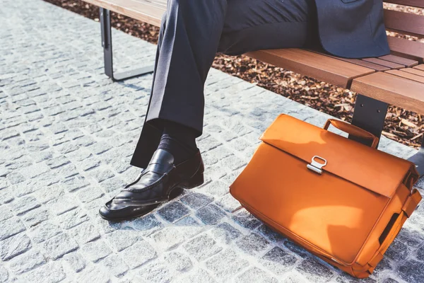 Geschäftsmann sitzt mit Aktentasche auf einer Bank — Stockfoto