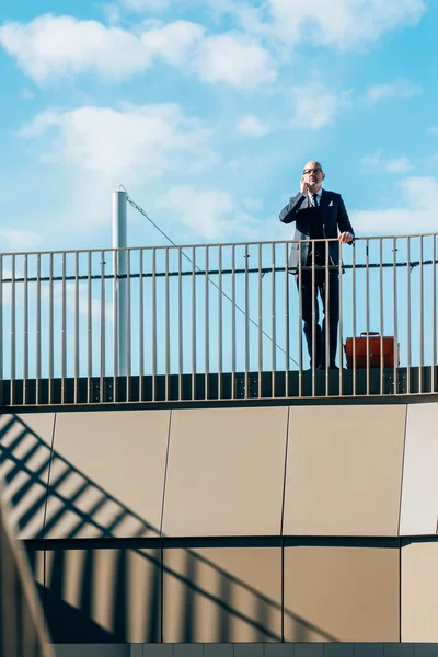 Geschäftsmann lehnt am Geländer und spricht mit Smartphone — Stockfoto