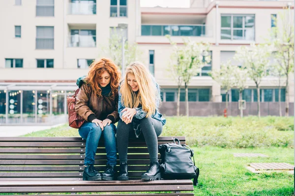 Vrouwen zitten op bankje in stadspark — Stockfoto