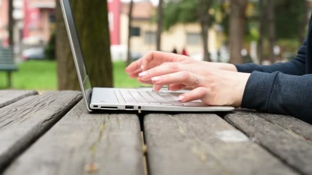 Frau tippt im Freien auf die Tastatur des Notebooks — Stockvideo