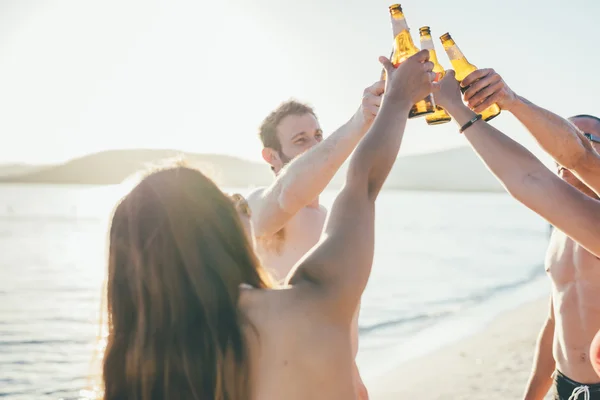 Freunde am Strand stoßen mit Bier an — Stockfoto