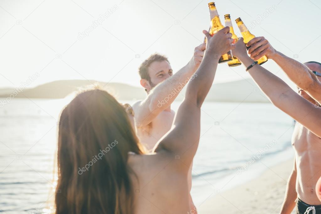 friends at beach toasting with beers