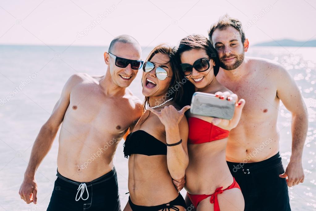 multiethnic friends at beach taking selfie