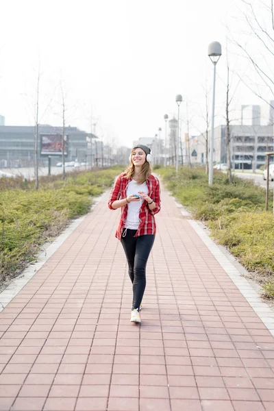 Girl walking and dancing through the street — Stock Photo, Image