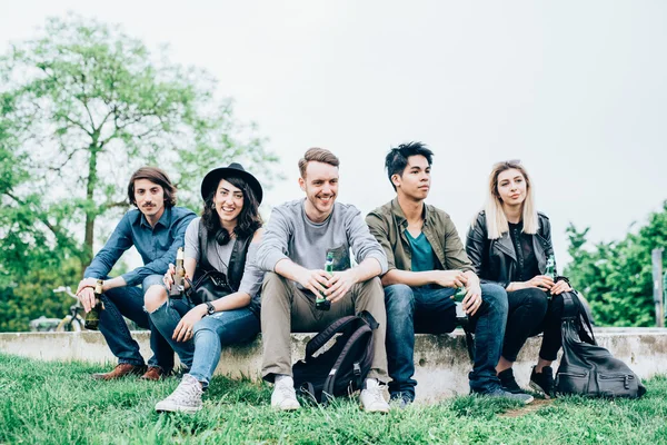 Multiethnic friends sitting on small wall — Stock Photo, Image