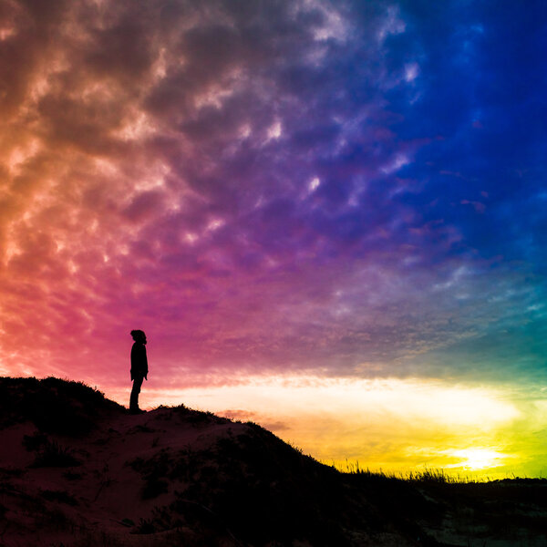 Back light silhouette of a man standing on a hill