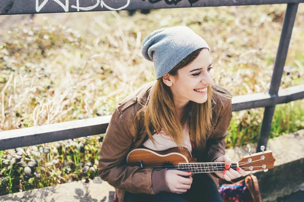 Woman outdoor in the city playing ukulele — Stockfoto