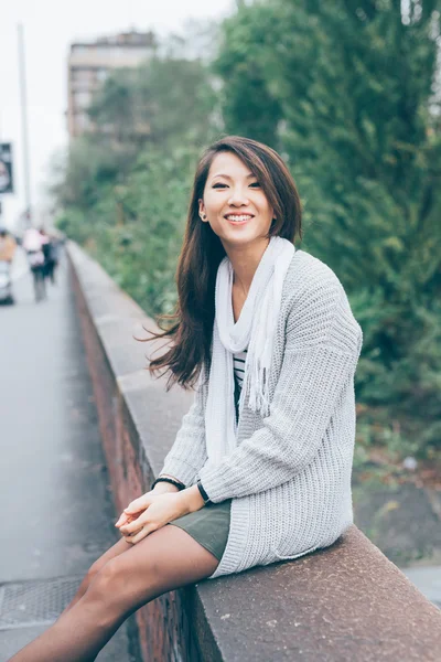 Asiatic woman sitting on small wall — Stock Photo, Image