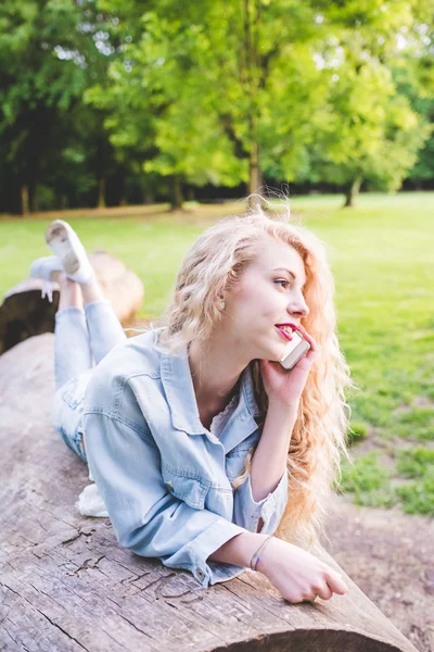 Woman lying on a trunk in a city park — Stockfoto