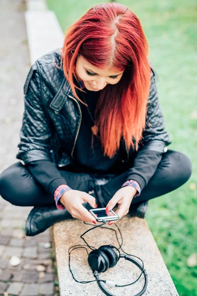 Mulher sentada ao ar livre segurando telefone inteligente — Fotografia de Stock