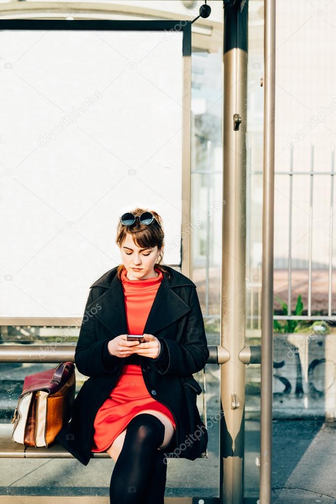 hipster woman sitting at bus stop