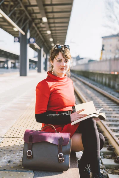 Γυναίκα που κάθεται σε μια πλατφόρμα σε ένα σιδηροδρομικό σταθμό — Φωτογραφία Αρχείου