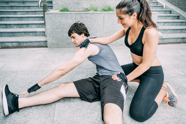 Sportive man and woman stretching together — Stock Photo, Image