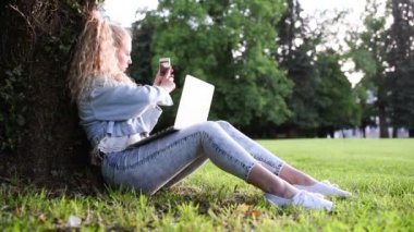 sarışın kadınla çimenlerin smartphone kullanarak üzerinde