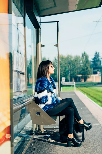 Kvinna som sitter vid busshållplatsen — Stockfoto