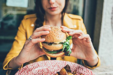 woman sitting holding an hamburger 