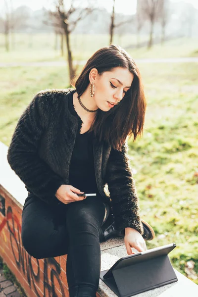 Woman sitting in city park using tablet — Stok fotoğraf