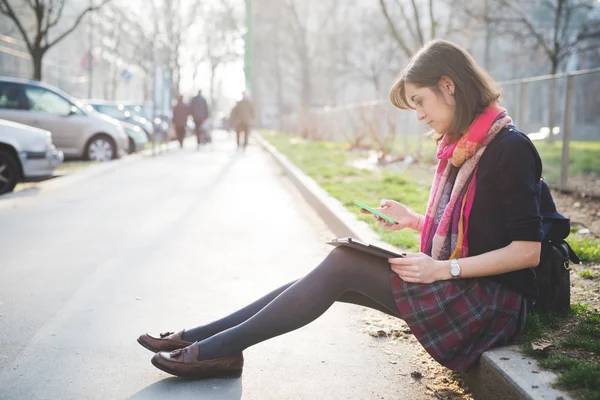 Женщина сидит на тротуаре с помощью планшета — стоковое фото