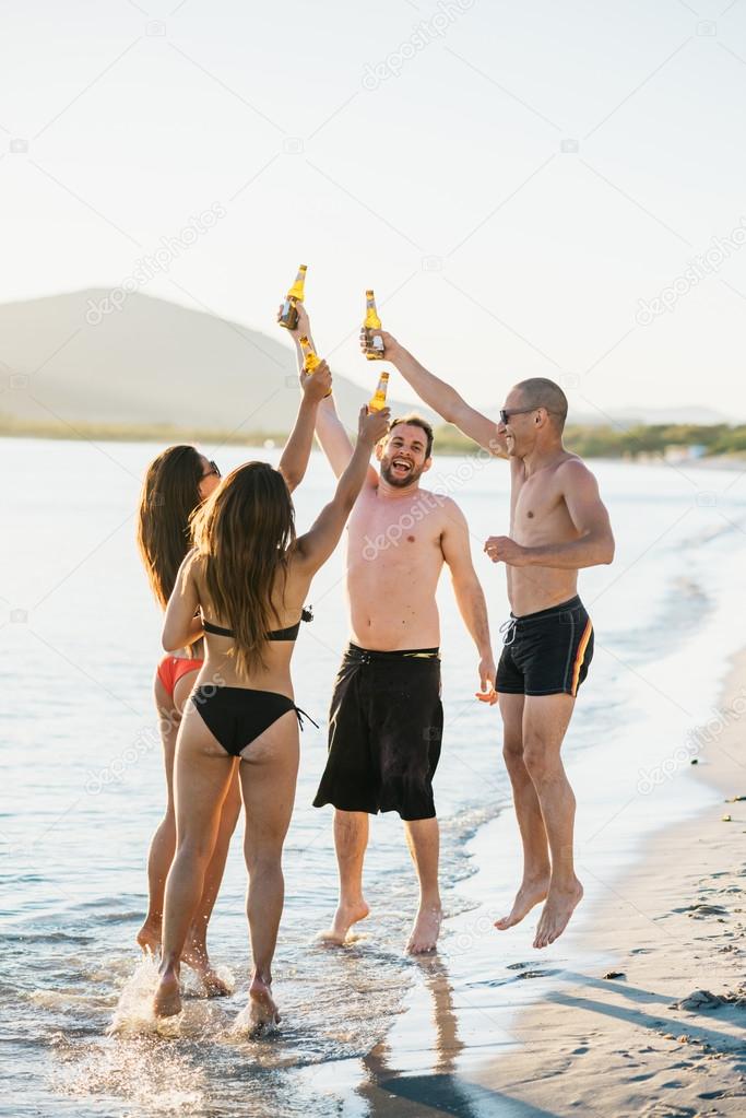 friends at beach toasting with beers 