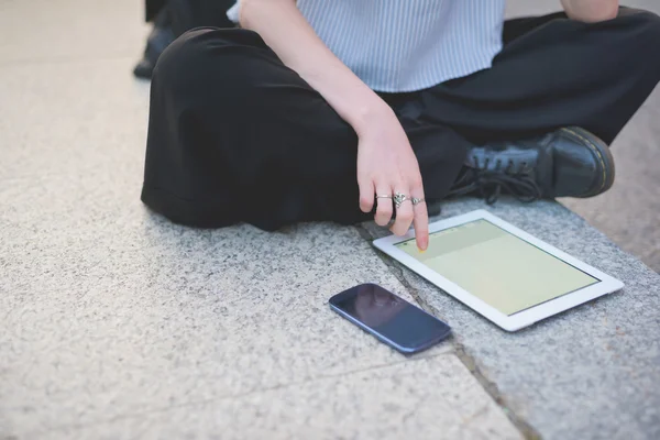 Woman sitting on a sidewalk using devices — Stock Photo, Image