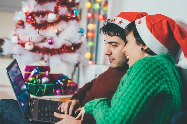 Par med santa claus hattar med hjälp av dator — Stockfoto