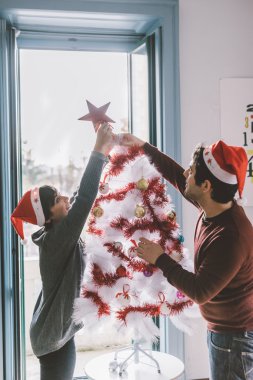 Erkek ve kadın Noel ağacı süslüyorlar.