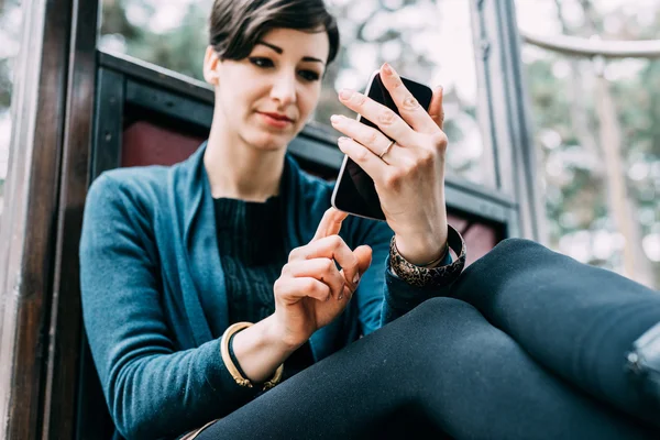 Femme aux cheveux bruns tenant un smartphone — Photo