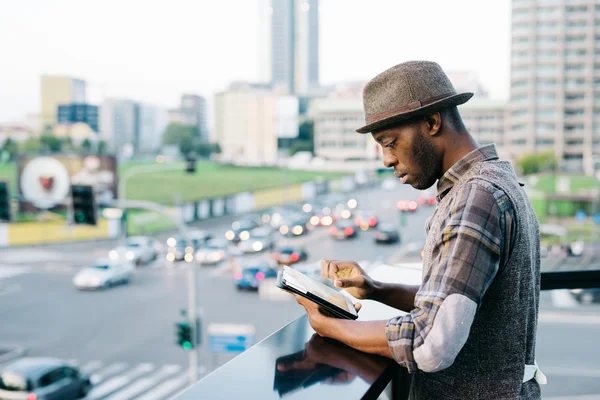 Afro hombre en ciudad golpeando con la tableta —  Fotos de Stock