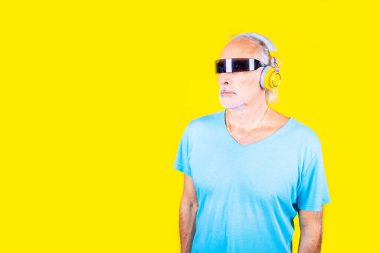 Sarı arka planda akıllı gözlükler takan yaşlı beyaz bir adam - arka planda izole edilmiş bilim kurgu gözlükleri takan yaşlı bir erkek - artırılmış gerçeklik, uygulanabilir teknoloji, bilim kurgu konsepti