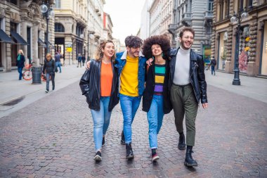 Bir grup arkadaş turist birlikte yürüyorlar. Şehir merkezinde açık havada kucaklaşıyorlar. Geziyorlar, eğleniyorlar, gülümsüyorlar ve tatilin tadını çıkarıyorlar.