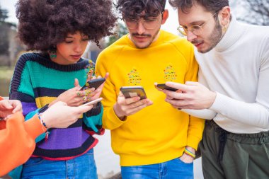 Cep telefonu kullanan çok ırklı arkadaşlar grubu - emoji ve ifadeleri takip eden ve sohbet eden teknoloji eğilimlerine bağımlı gençler - sosyal medya, bağımlılık, sohbet kavramı