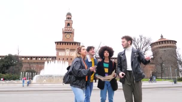 スローモーション4つの多民族の若い友人旅行者屋外検索観光マップガイドを使用して観光やスマートフォンの手を握って街を歩く新しい場所を発見 — ストック動画