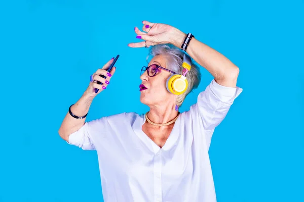 Old Woman Enthusiastic Dancing Listening Music Holding Smartphone Isolated Blue — Stock Photo, Image