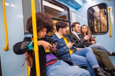 Akıllı telefon kullanarak metroda seyahat eden dört etnik gruptan oluşan bir grup sosyal medyadaki viral sosyal eğilimlere bakarak birlikte konuşuyorlar.