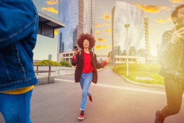 Şehirdeki üç genç arkadaş ellerinde akıllı telefonlarıyla koşuşturuyor ve araçları yakalamaya çalışıyorlar.