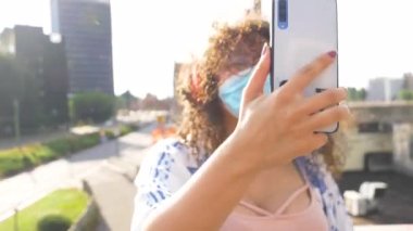 Koruma maskesi takan genç bir ırk kadını sosyal medyada canlı yayında ya da akıllı telefonları kullanarak arkadaşlarıyla görüntülü konuşma yapıyor.
